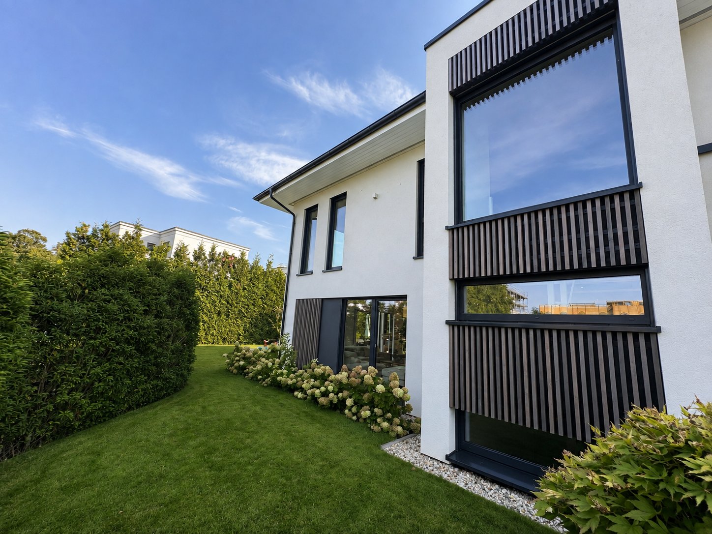Fassade mit Holzlamellen und Garten
